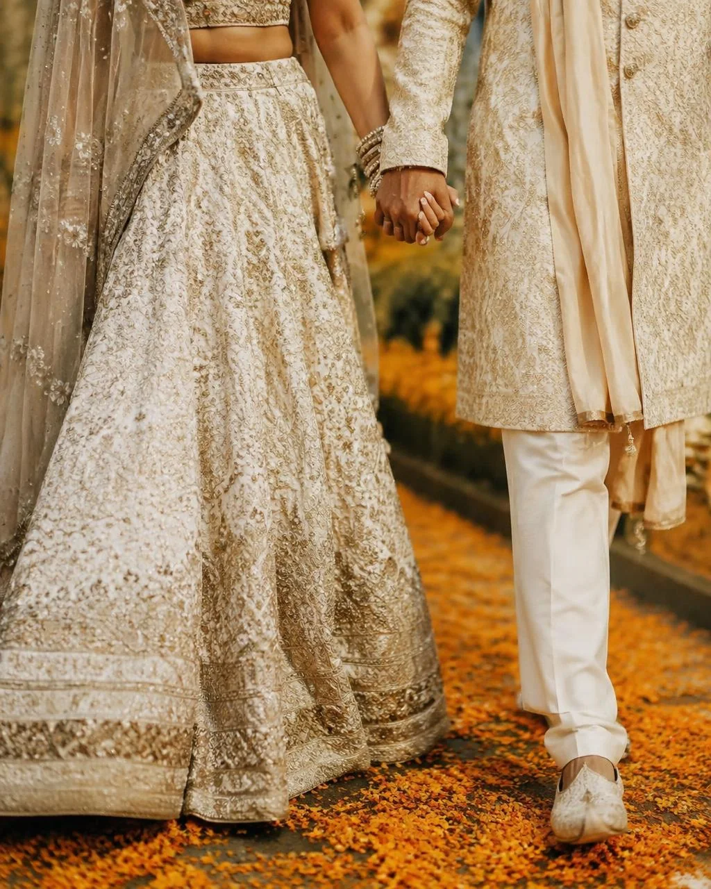 Couple walking through marigold petals